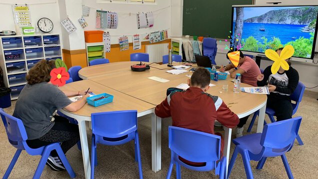 Mehrere Schülerinnen und Schüler arbeiten an einem runden Tisch.